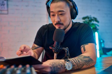 Dövmeleri olan yakışıklı bir Asyalı stüdyosunda bir podcast kaydediyor..