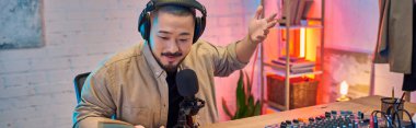 Kulaklıklı bir adam stüdyosunda bir podcast kaydediyor, doğrudan mikrofona bakıyor..
