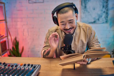 Kulaklıklı ve mikrofonlu yakışıklı bir Asyalı podcast 'ini bir ev stüdyosunda kaydediyor..