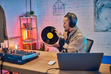 Kulaklıklı Asyalı bir adam, canlı yayın yaparken dikkatle plak dinliyor..