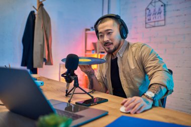 Bronz gömlekli yakışıklı bir Asyalı stüdyoda podcast çekiyor..