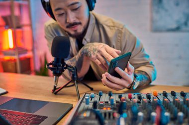 Yakışıklı bir Asyalı telefonuna podcast stüdyosunda konsantre oluyor..