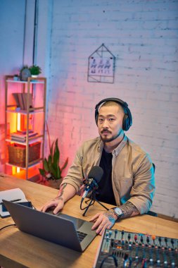 Kulaklık takan yakışıklı bir Asyalı, stüdyosunda bir podcast kaydediyor..