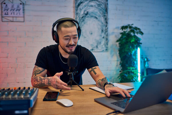 Красивый азиат записывает подкаст в своей студии..