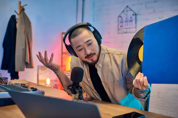 stock image A man in a home studio setup with a microphone and a record.