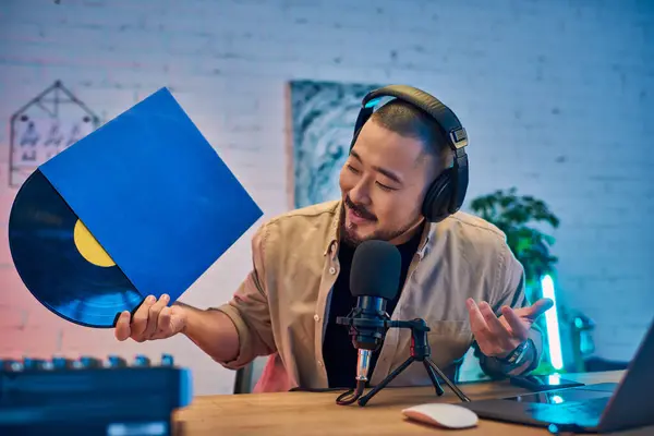 stock image A man in a studio setting records a podcast while holding a vinyl record.