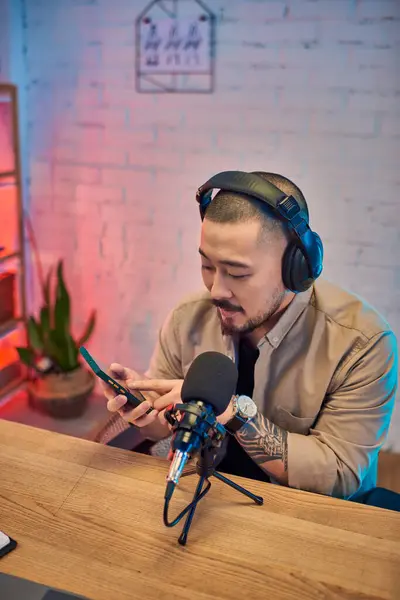 stock image A handsome Asian man records a podcast in his studio.