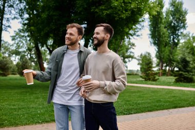 Sıradan giyinmiş iki sakallı adam parkta yürürken kahkahalarını paylaşıyor..