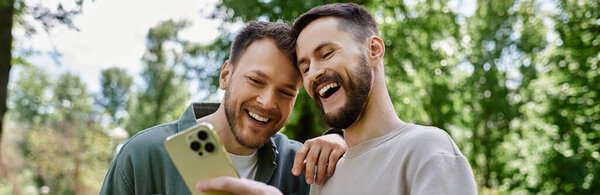 Два бородатых гея смеются вместе в парке.
