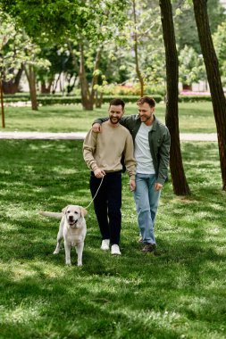 A gay couple walks with their labrador retriever through a lush green park, enjoying a sunny day together. clipart