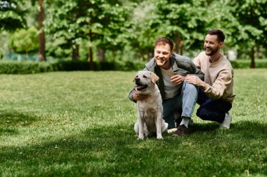 Sakallı eşcinsel bir çift güneşli bir öğleden sonrayı labrador av köpeğiyle parkta geçirir..