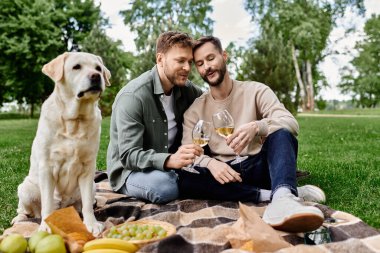 A bearded gay couple enjoys a picnic with their labrador retriever in a lush green park. They are sharing a bottle of wine and appear to be having a romantic and relaxing time. clipart