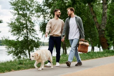 Two bearded men walk together in a green park with their labrador retriever, enjoying a picnic on a sunny day. clipart