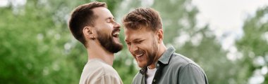 A gay couple with beards enjoys a sunny day in a green park, laughing together. clipart