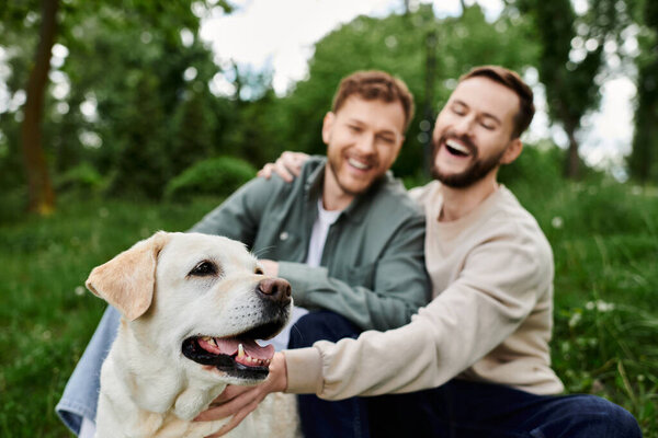 Бородатая гей-пара смеется и гладит свою собаку-лабрадора в пышном зеленом парке.