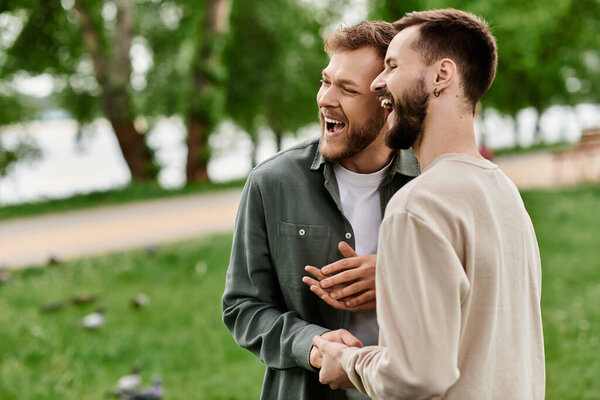 Двое бородатых мужчин смеются вместе в солнечном зеленом парке.