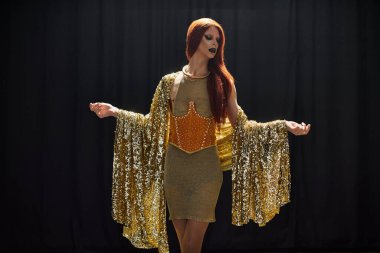 Altın pullu bir şal ve dramatik bir poz giymiş bir diva..