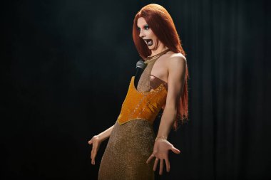 Işıldayan altın elbisesiyle göz kamaştırıcı bir travesti karanlık bir sahnede sahneye çıkar ve dinleyicileri enerjik varlığıyla büyüler..
