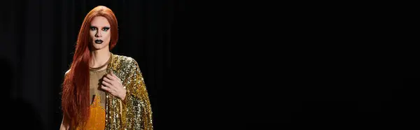 stock image A drag performer in a gold sequined outfit stands against a dark background.