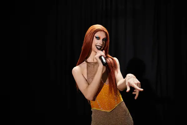 stock image A drag performer sings into a microphone on stage, showcasing their dazzling attire and confident presence.