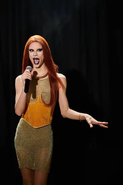 stock image A drag performer wearing a sparkling gold dress sings into a microphone on stage.