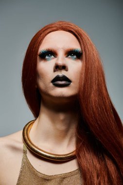 Altın kıyafetli bir travesti dramatik bir ifadeyle yukarı bakar..