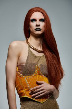 Bir travesti göz alıcı bir altın ve sarı elbiseyle poz verir..