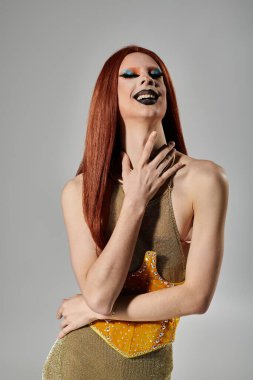 Parlak altın elbiseli bir travesti neşeyle güler..