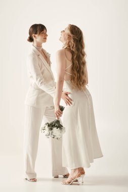 Beyaz düğün kıyafetli iki güzel gelin birlikte mutlu bir anı paylaşıyor..