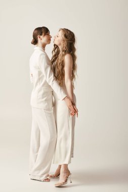 Beyaz elbiseli iki güzel gelin düğün törenlerinde birbirlerine sarılıyorlar..