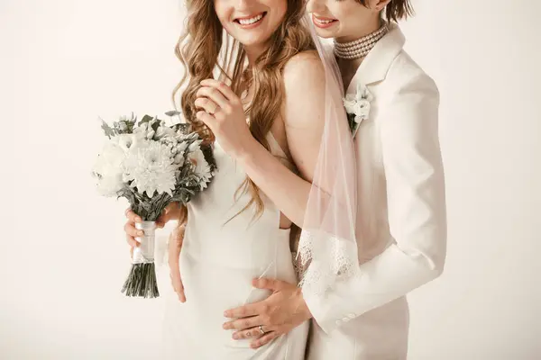 stock image A young lesbian couple, both dressed in white, share a tender moment during their wedding ceremony.