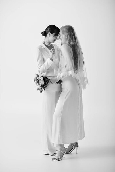 Two brides in white attire embrace during their wedding ceremony, radiating joy and love.