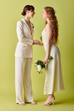 Beyaz giyinmiş lezbiyen bir çift, düğün törenlerinde gülümseyip el ele tutuşuyorlar..