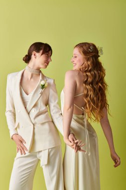 A lesbian couple in white attire share a loving moment during their wedding ceremony, set against a vibrant green background. clipart