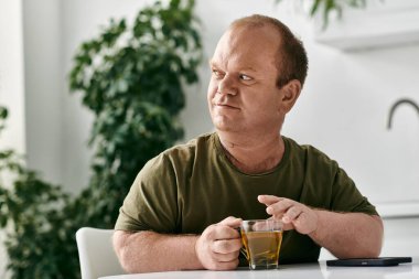 A man with inclusivity in casual attire relaxes with a cup of tea at home. clipart