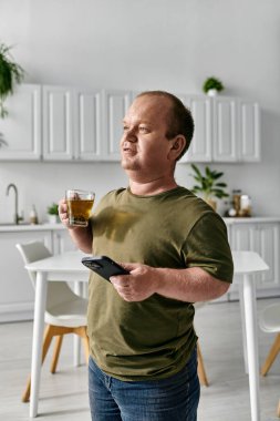 Kapsayıcı bir adam evinde akıllı telefonunu kullanırken tesadüfen içecekten zevk alır..