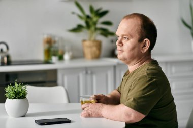 A man with inclusivity in casual attire enjoys a beverage at home, contemplating the day ahead. clipart