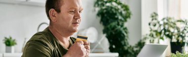 Günlük kıyafetleri olan bir adam evde otururken kredi kartı tutar..