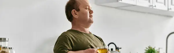 stock image A man with inclusivity enjoys a cup of tea in his cozy kitchen.