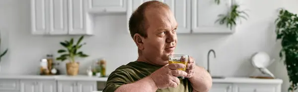 stock image A man with inclusivity enjoys a beverage at home, looking contemplative.