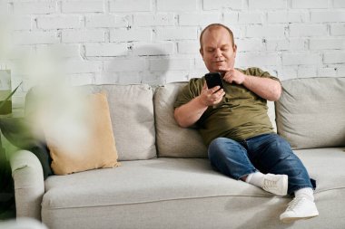 Kapsamlı bir adam oturma odasındaki bir kanepede oturmuş telefonuna bakıyor..