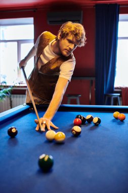 Bir adam yeşil keçeli masadaki bilardo toplarını hedef alıyor..