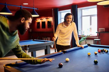 Arkadaşlar rahat bir ortamda bilardo oynarlar, biri atış yaparken diğeri seyreder..