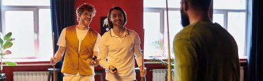 Arkadaşlar bilardo masasının etrafında durur, güler ve bilardo oynarlar..