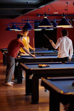 Arkadaşlar loş bir odada bilardo oynar, eğlenceli bir akşamın tadını çıkarırlar..