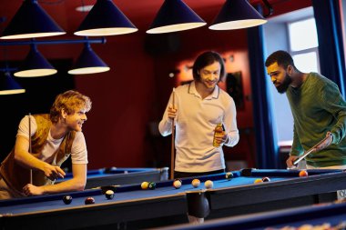 Arkadaşlar loş bir odada bilardo oynamaktan zevk alırlar. Oynarken gülüp konuşurlar..