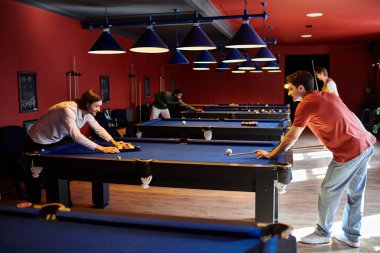 Arkadaşlar iyi aydınlatılmış bilardo odasında bilardo oynarlar..