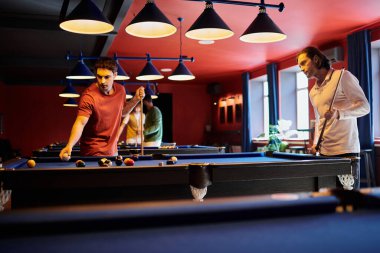 Arkadaşlar loş bir odada bilardo oynarlar..