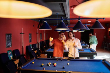 Arkadaşlar loş ışıklı bir odada birlikte bilardo oynarlar..