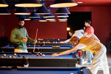 Arkadaşlar, kırmızı duvarlı loş bir odada bilardo oynamaktan hoşlanırlar..